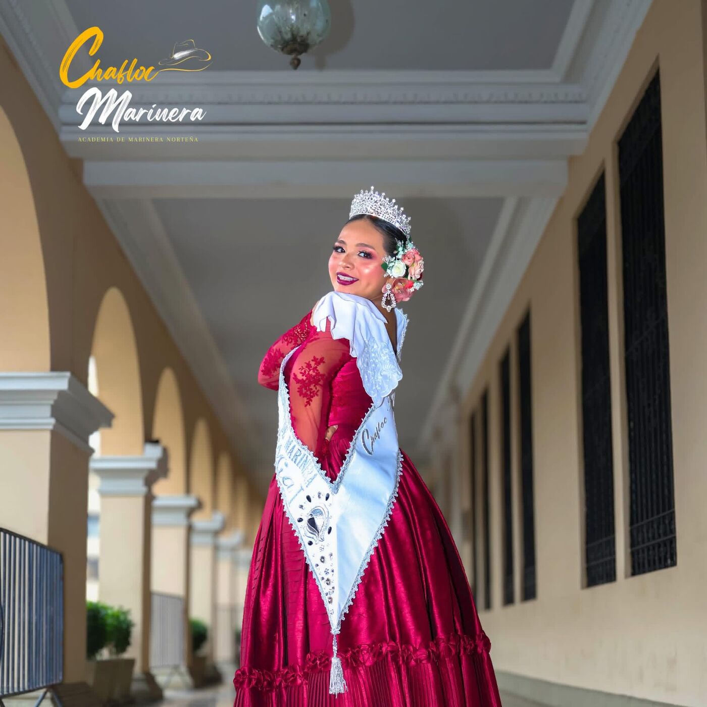 Alumna con corona y banda, traje rojo